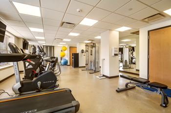 a gym with cardio equipment and weights in a hall with a mirror