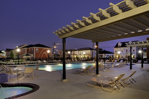 a swimming pool with chairs and tables at night