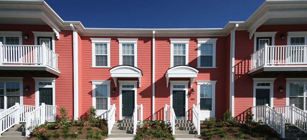 a row of red apartments with white steps and balconies