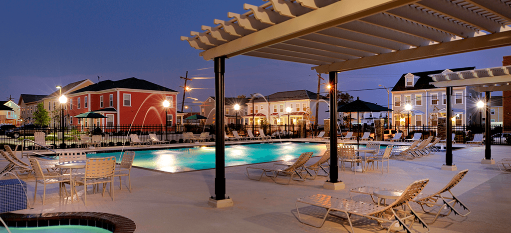 a swimming pool with chairs and tables at night