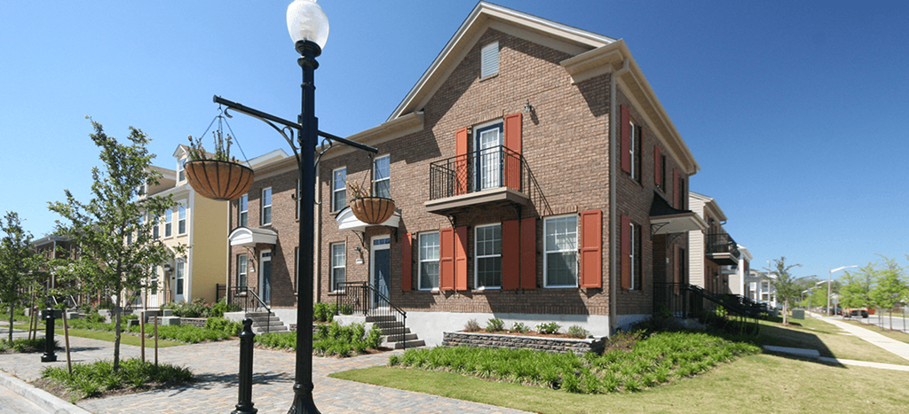 a brick apartment home with red shutters and a street light