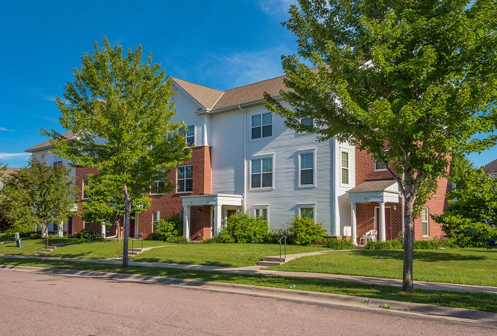 an apartment building on the corner of a street with trees