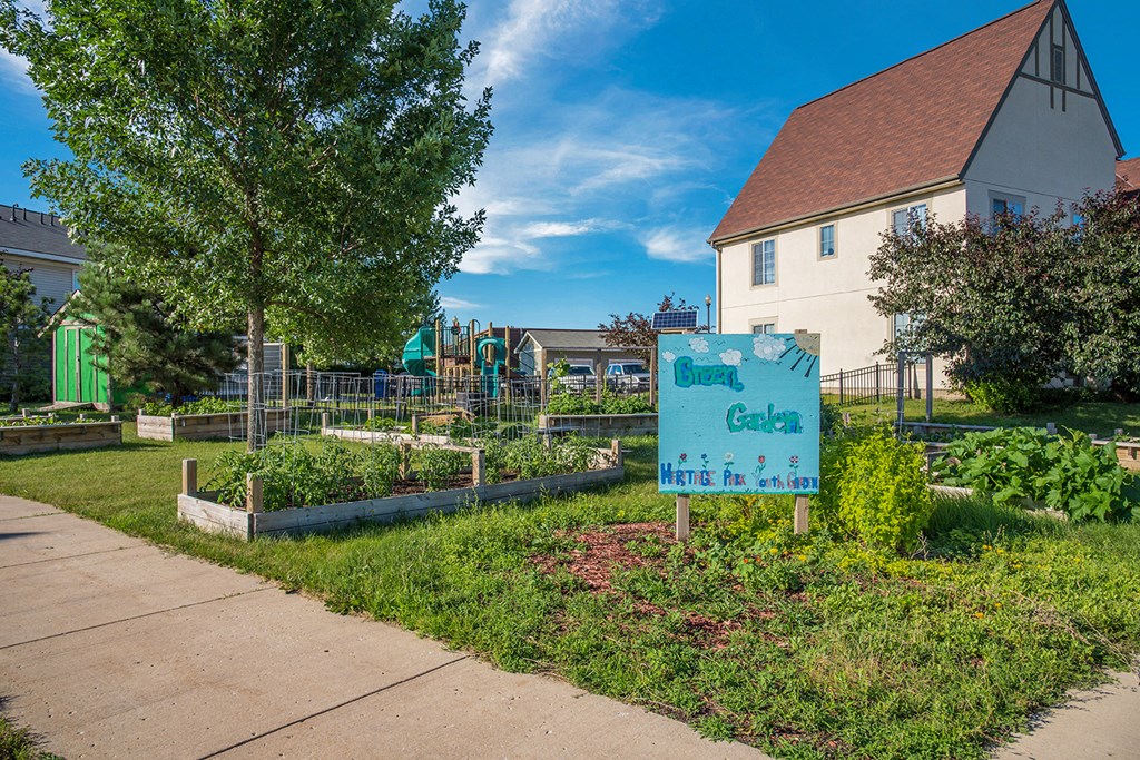 a community garden with a sign in front of a house