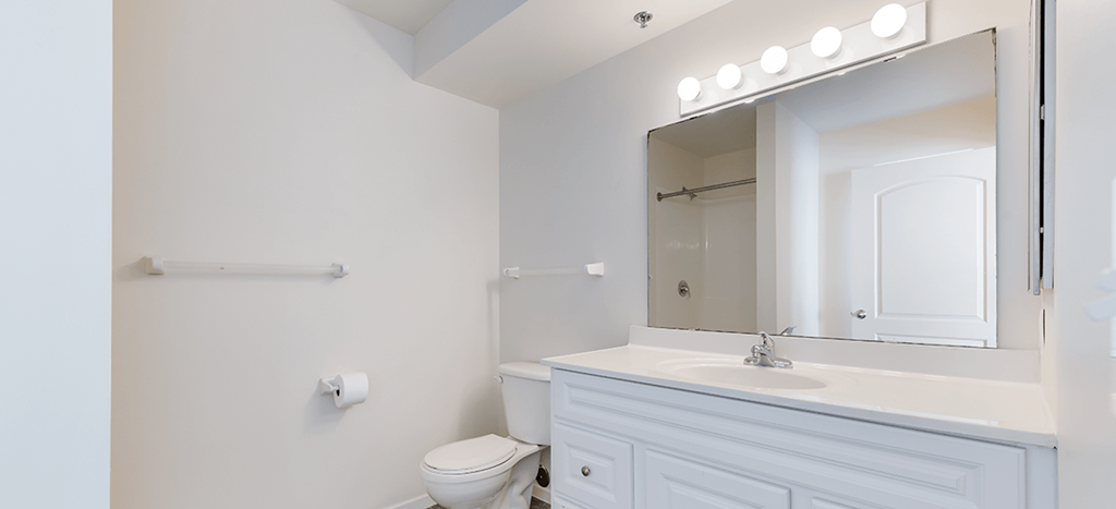 a bathroom with a sink and a mirror and a toilet at Heritage Park Apartments