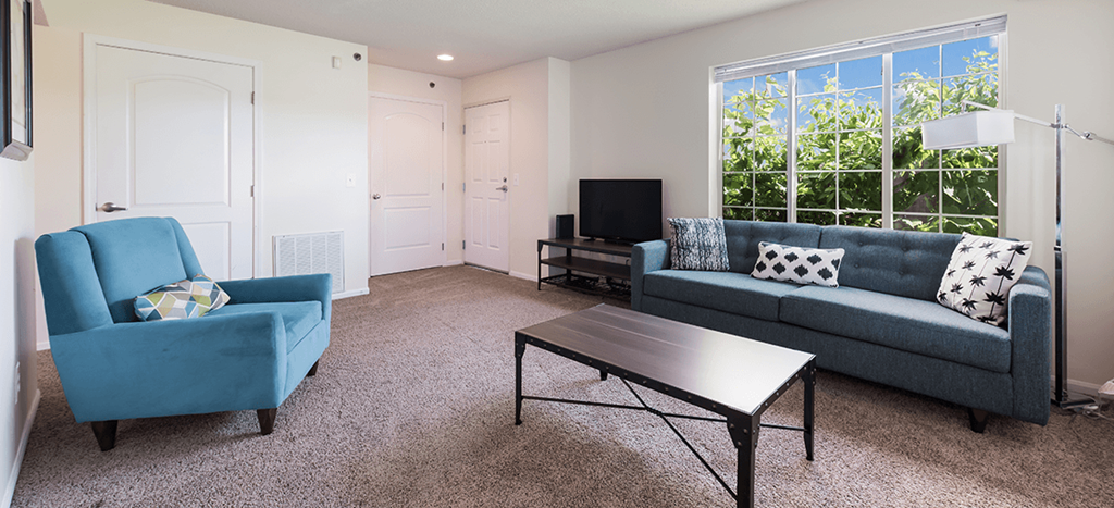a living room with a blue couch and a coffee table at Heritage Park Apartments