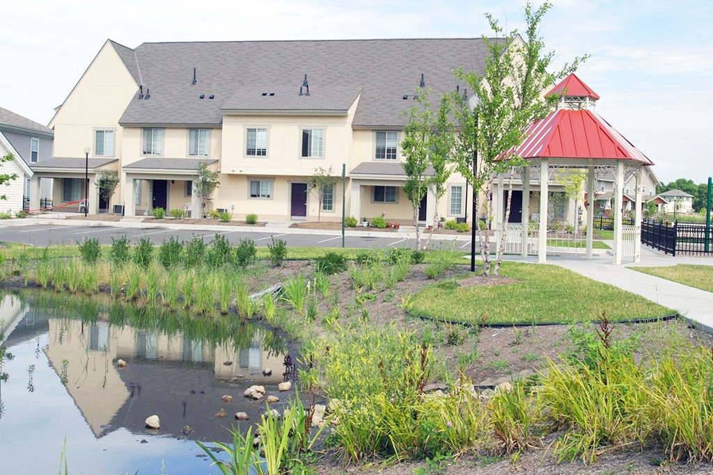 a pond in front of a building with a gazebo at Heritage Park Apartments and Townhomes in Minneapolis, MN