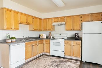 a kitchen with white appliances and wooden cabinets at Horace Mann Apartments and Townhomes in Gary, IN
