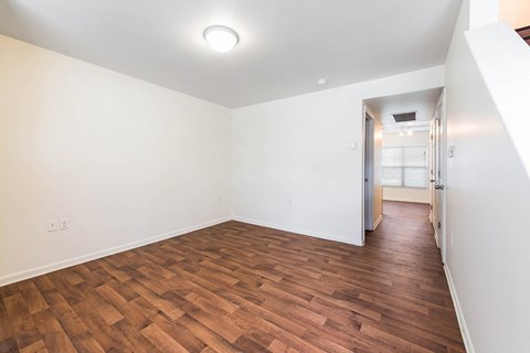 an empty living room with wood flooring and white walls at Horace Mann apartments and townhomes in Gary, IN