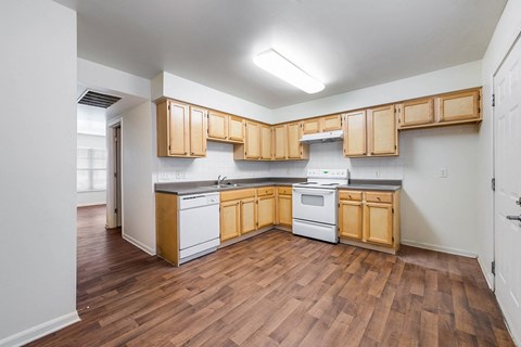 an empty kitchen with wooden cabinets and white appliances at Horace Mann apartments and townhomes in Gary, IN