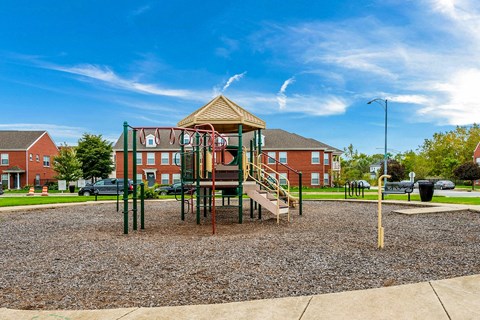 a playground with a swing set in front of a building at Horace Mann apartments and townhomes in Gary, IN