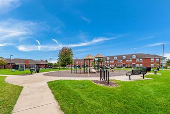 a park with a playground, bike racks, and benches in front of a building at Horace Mann apartments and townhomes in Gary, IN