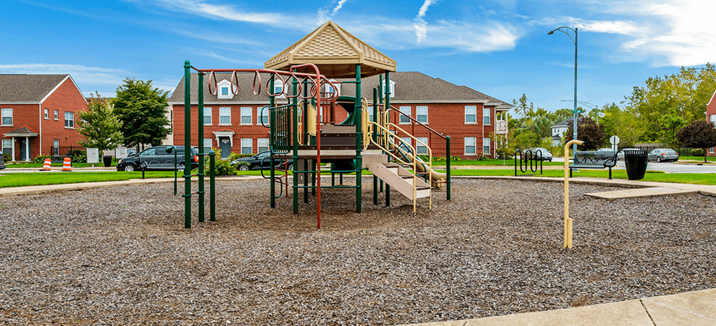 a playground with an apartment building in the background at Horace Mann