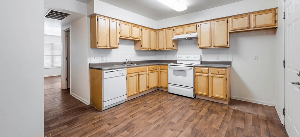 an empty kitchen with wooden cabinets and white appliances at Horace Mann apartments