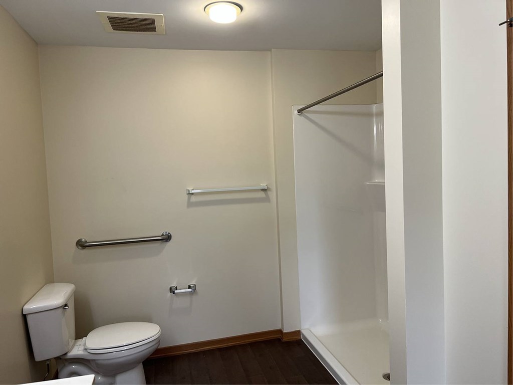 A white toilet sits in a small bathroom with a white shower curtain.