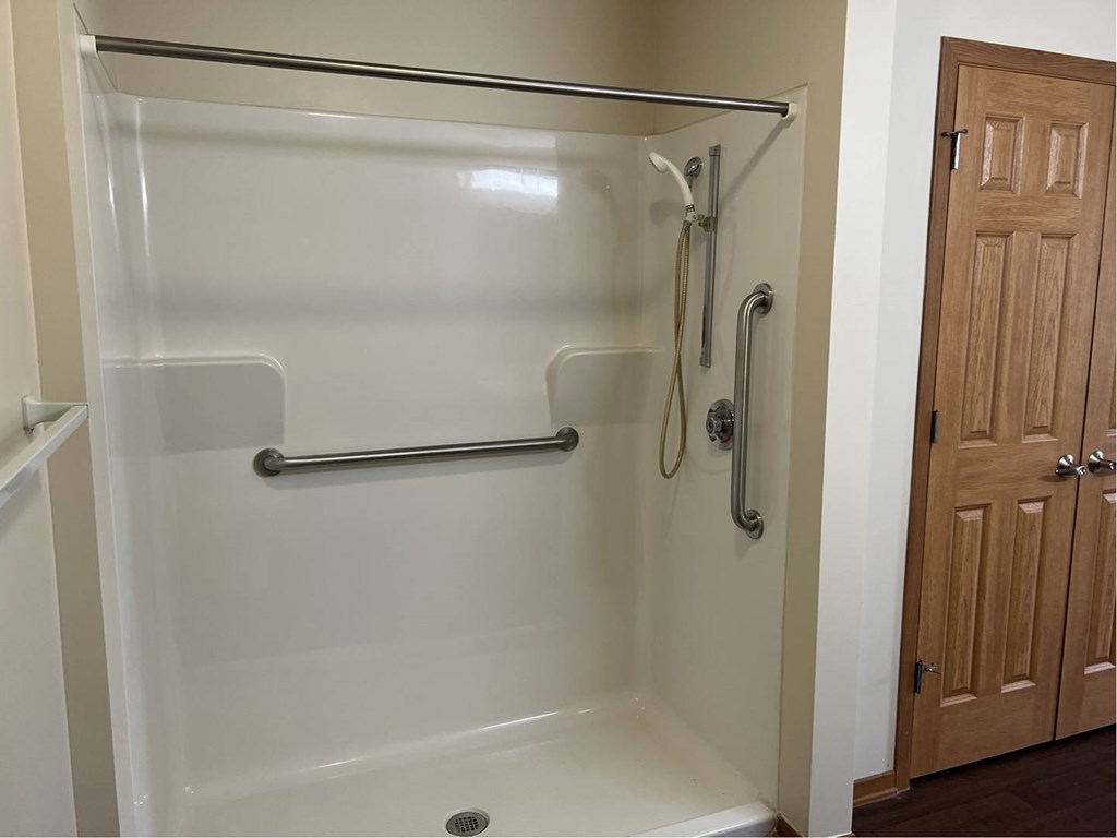 A white shower stall with a door and a shower head.