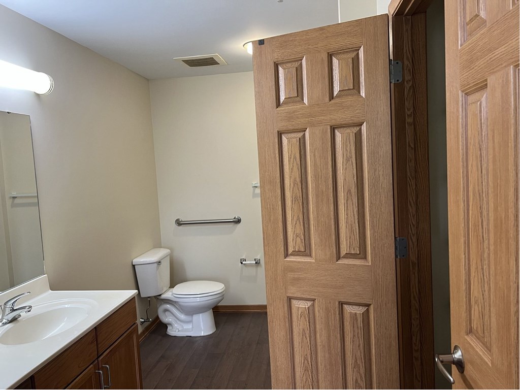 A bathroom with a toilet, sink, and mirror.