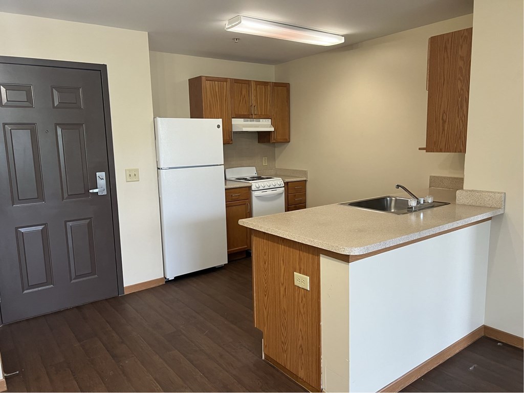 A kitchen with a white refrigerator and wooden cabinets.