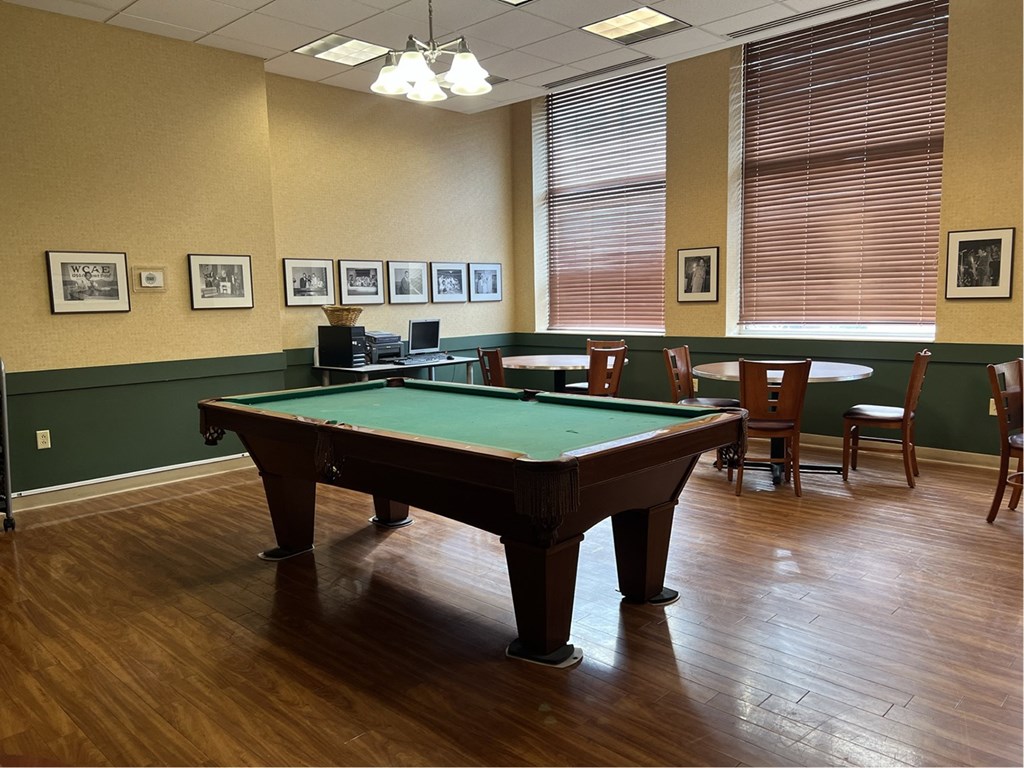 A pool table in a room with wooden floors and green walls.
