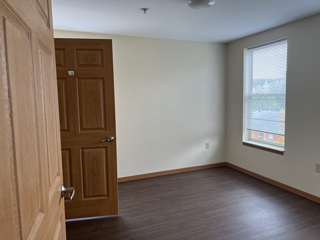 A room with a wooden door and a window with blinds.