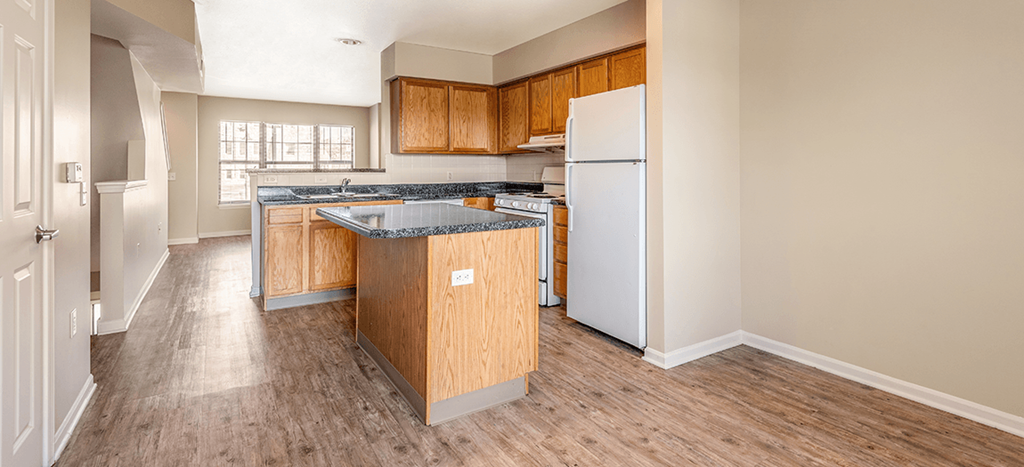 an empty kitchen with wooden cabinets and a white refrigerator
