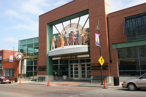 A building with a large mural on the front and a pedestrian crossing sign.