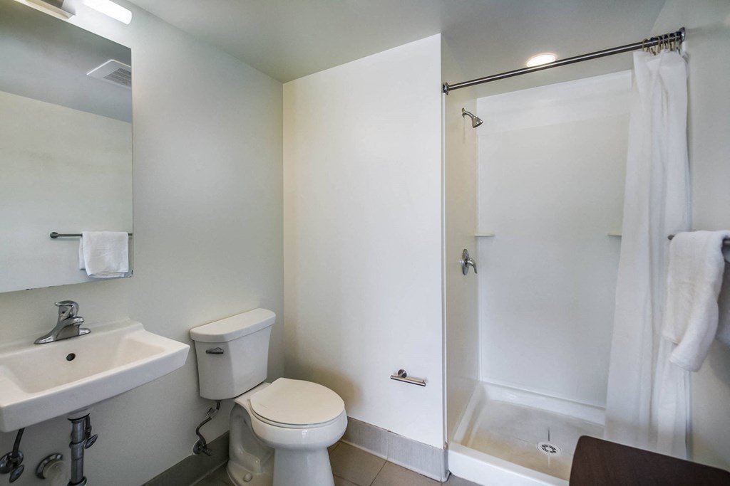 A white bathroom with a toilet, sink, and shower.