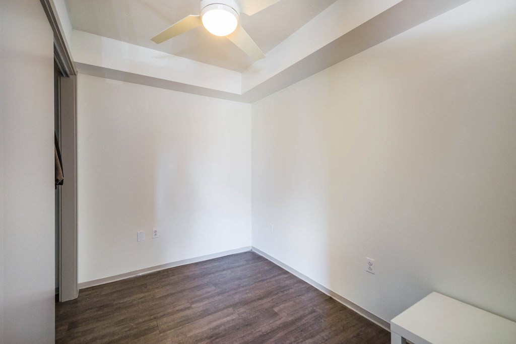 A room with a ceiling fan and wooden flooring.