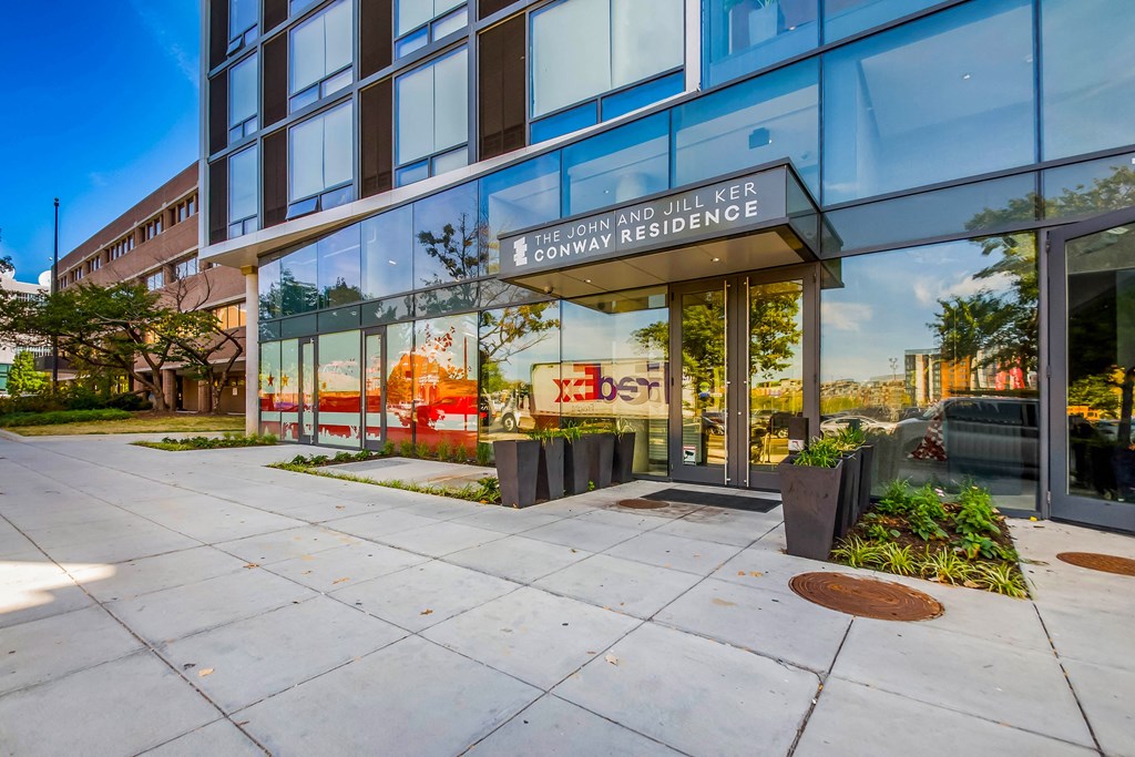 The entrance to a building with a glass facade and a sign that reads "The John and Jill Ker Conway Residence.".