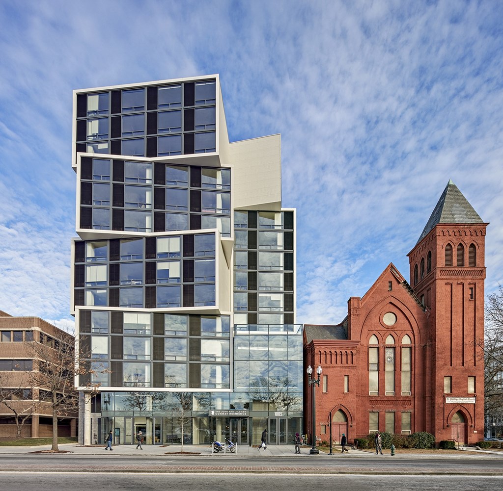 A modern glass building stands next to an older red brick building.