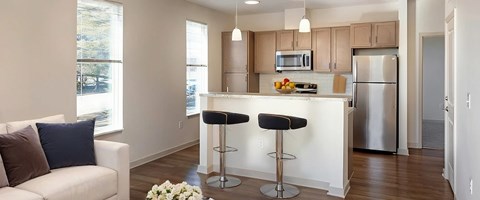 A kitchen with a white counter and bar stools.