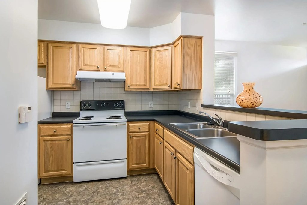 A kitchen with wooden cabinets and a white stove top oven.
