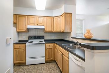 A kitchen with wooden cabinets and a white stove top oven.