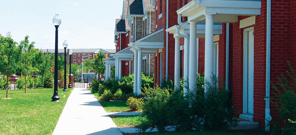 a sidewalk in front of a row of brick houses
