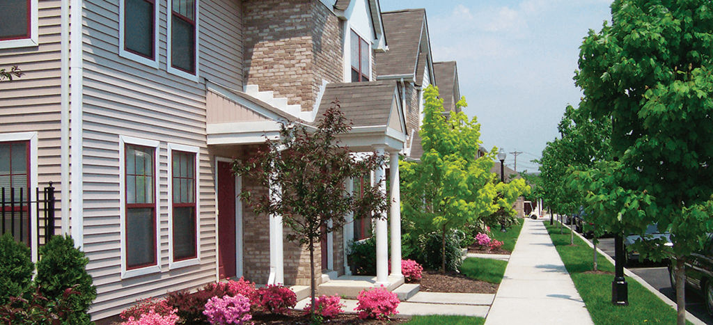 a row of houses on a street with trees and flowers
