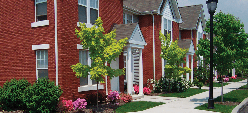 a sidewalk in front of a brick apartment building