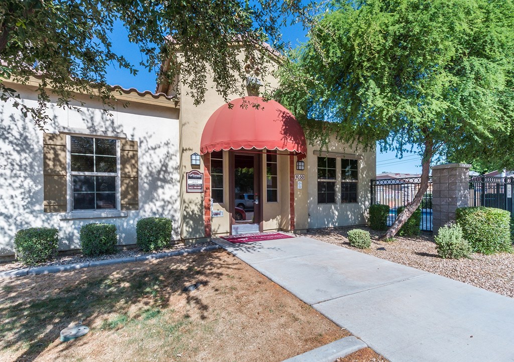A white building with a red awning and a small porch.
