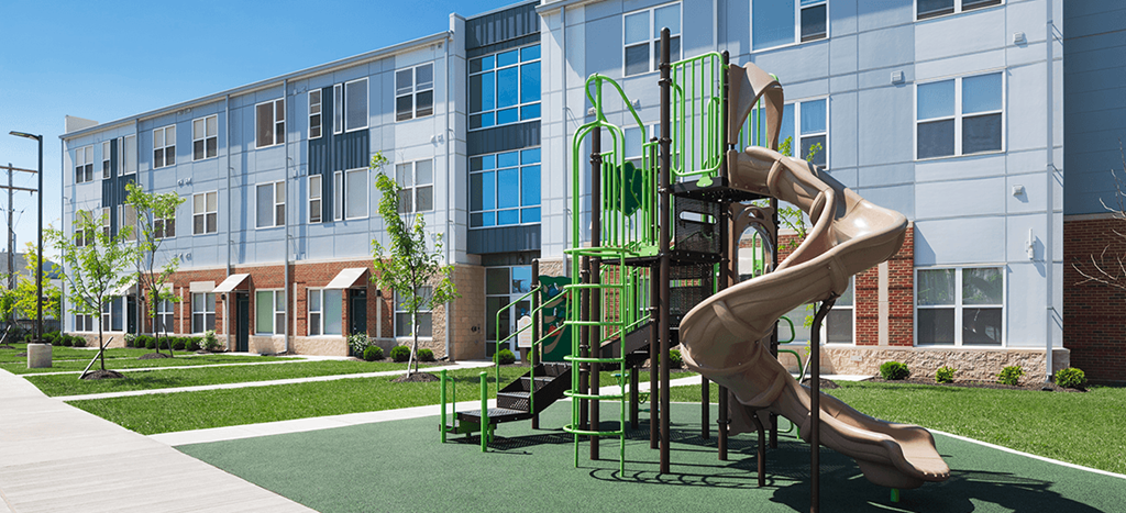 a playground with a large slide in front of an apartment building