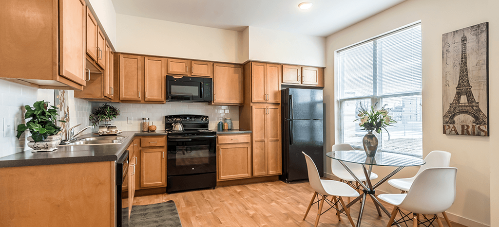 a kitchen with wooden cabinets and black appliances and a table and chairs