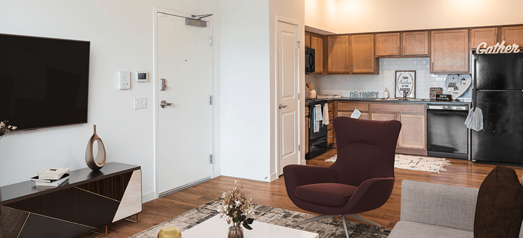 a living room and kitchen with a black refrigerator and a chair