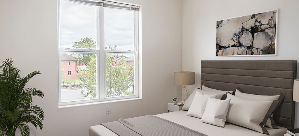 a bedroom with a large window and a bed with white pillows