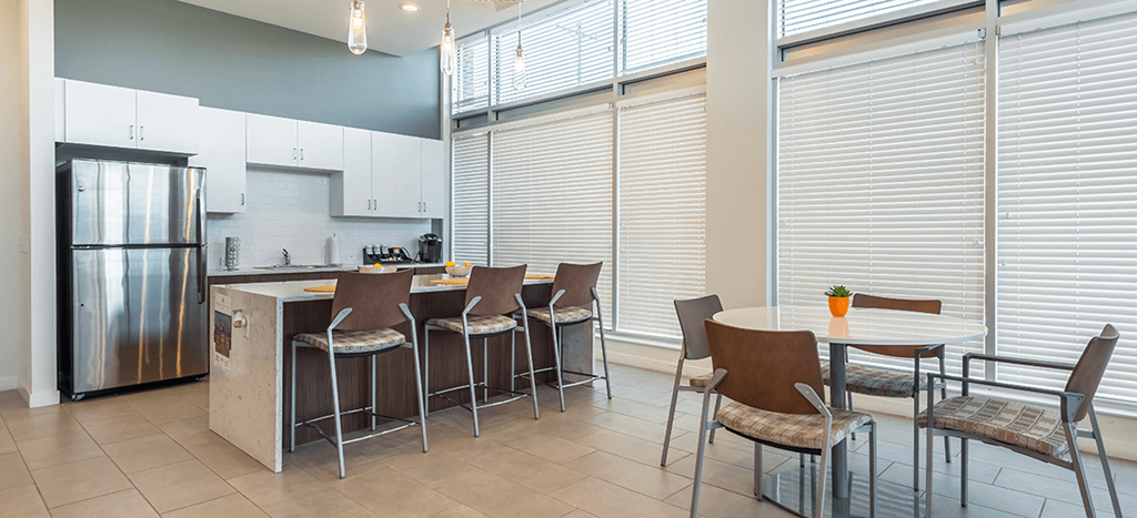 Legacy Pointe at Poindexter clubhouse with a dining area with a table and chairs and a kitchen with a refrigerator