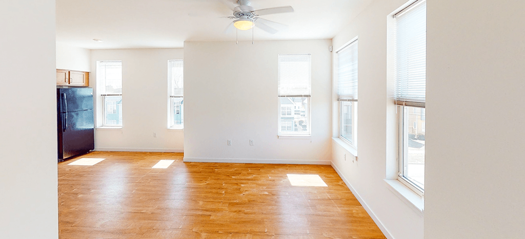 an empty living room with wood floors and a ceiling fan