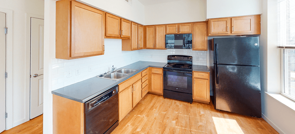 a kitchen with wooden cabinets and a black refrigerator