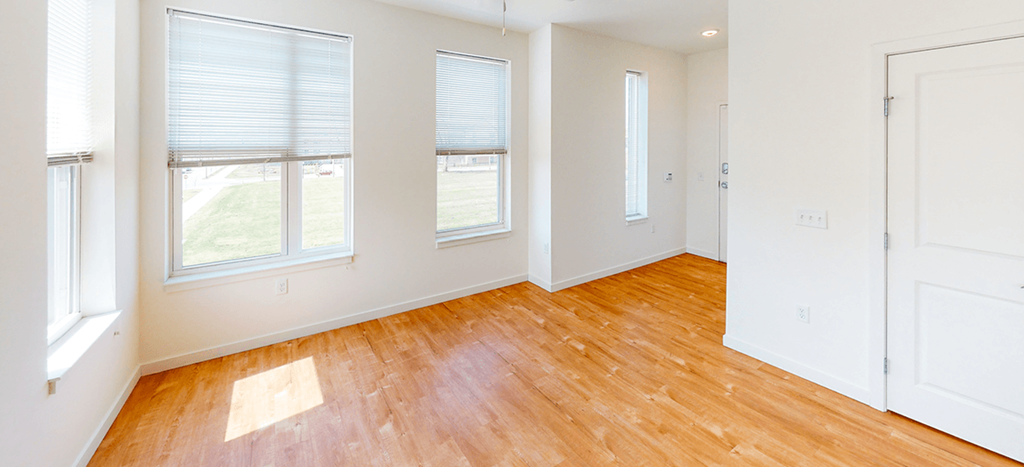 an empty living room with wood floors and white walls