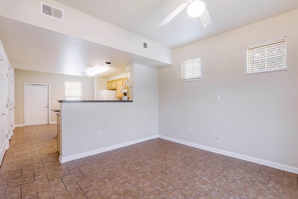 the living room and kitchen of an empty home with tile flooring