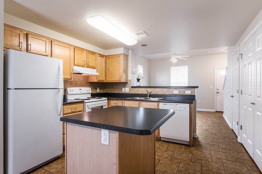 a kitchen with white appliances and wooden cabinets and a black counter top