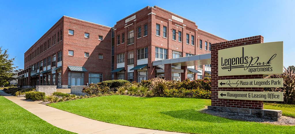 a large brick building with a sign for Legends Park Apartments