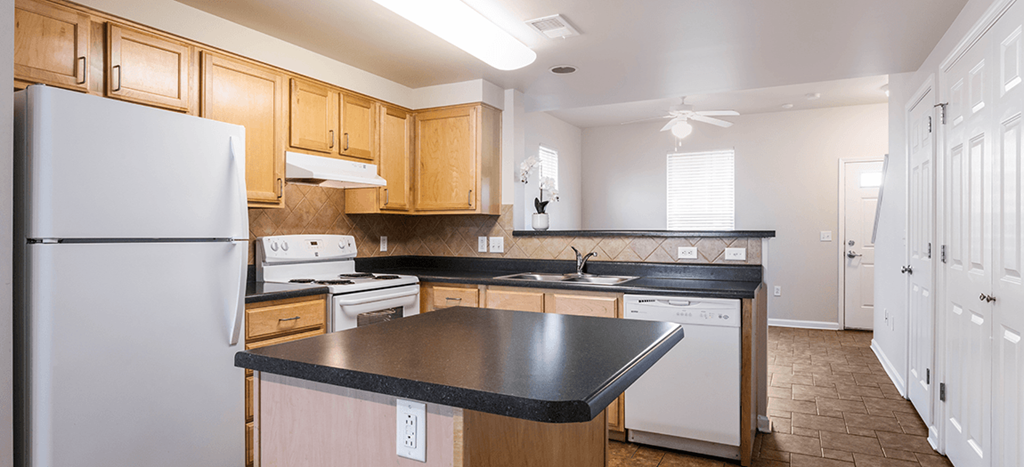 a kitchen with white appliances and wooden cabinets and black counter tops