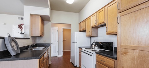 a kitchen with white appliances and black counter tops and wooden cabinets