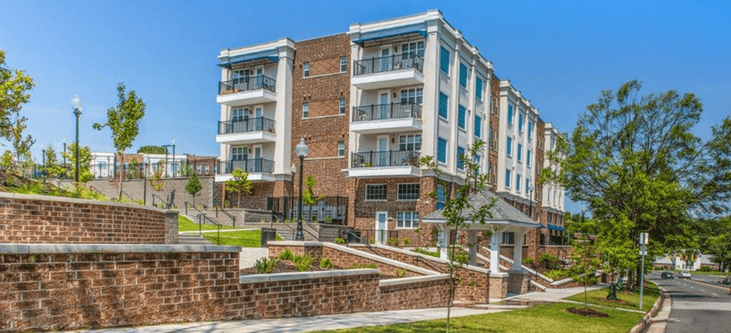 a large brick apartment building with stairs in front of it and tiered landscaping
